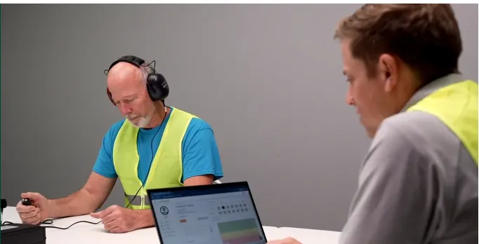 Audiometric hearing test in progress — employee wearing headphones during on-site testing session